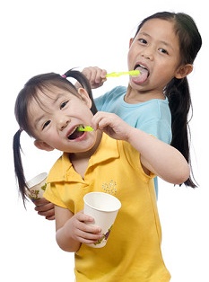 Photograph of two young children enjoying cleaning their teeth