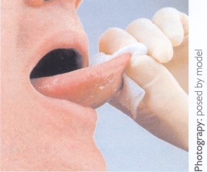 Photograph of a patient's tongue and mouth being examined dy a dentist